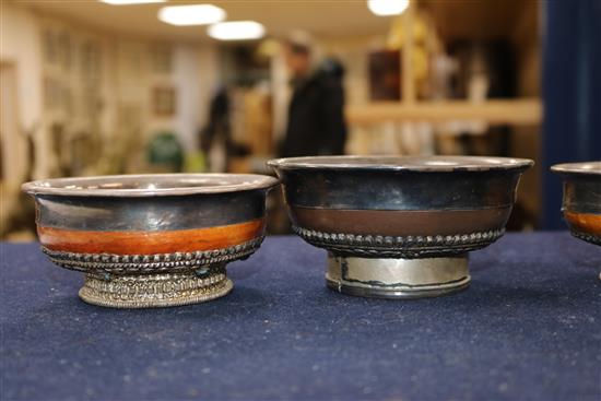 Four Tibetan white metal and wood bowls largest 10cm